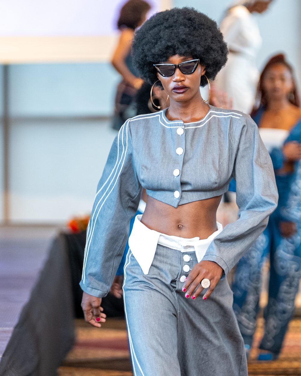 Model in a piped grey denim crop jacket and wide trousers on the runway