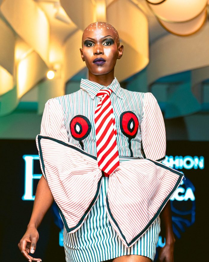 Model on the runway in a striped shirt dress with an oversized bow